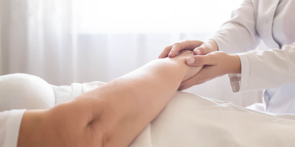 Odleżyny - zdjęcie przedstawia pracownika medycznego trzymającego pacjenta za rękę