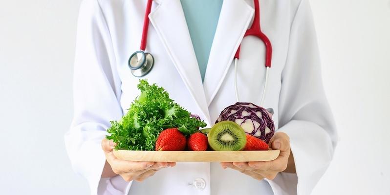 Dieta na zdrowe jelita - co jeść, aby czuć się lepiej. Lekarz trzyma tacę z warzywami i owocami.