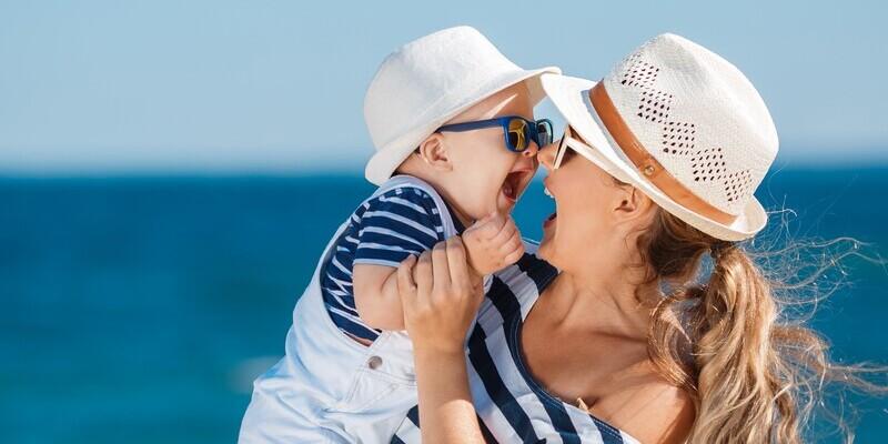 Przegrzanie organizmu - objawy, skutki uboczne. Mama z dzieckiem w kapeluszach i okularach przeciwsłonecznych.