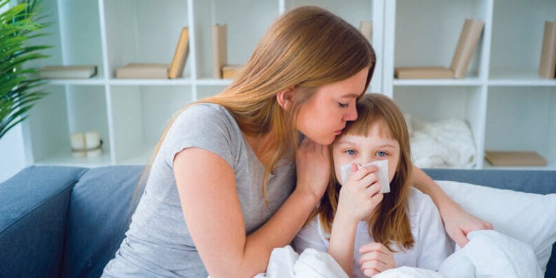 Powikłania po grypie u dzieci i dorosłych - mama przytula chorą córeczkę.