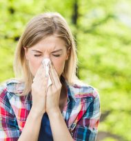 Woman with allergy symptom blowing nose